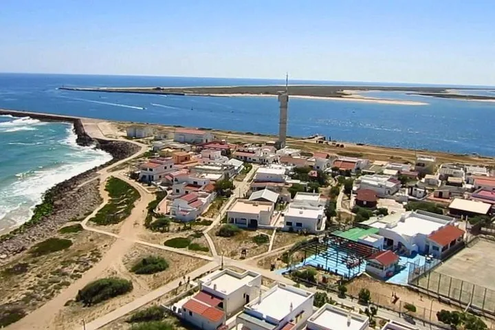 Luftaufnahme eines Küstendorfs mit einem hohen Turm und Meer