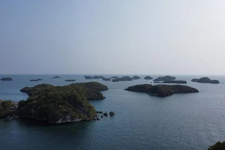 Panoramablick auf mehrere kleine, bewaldete Inseln, die über das Meer verstreut sind